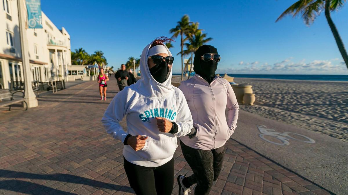 Maria Alonso, left, and Norvel Santora make their way down the Hollywood Beach Broadwalk as temperatures dip into the mid 40s on Saturday, Jan. 14, 2023, in Hollywood, Fla.