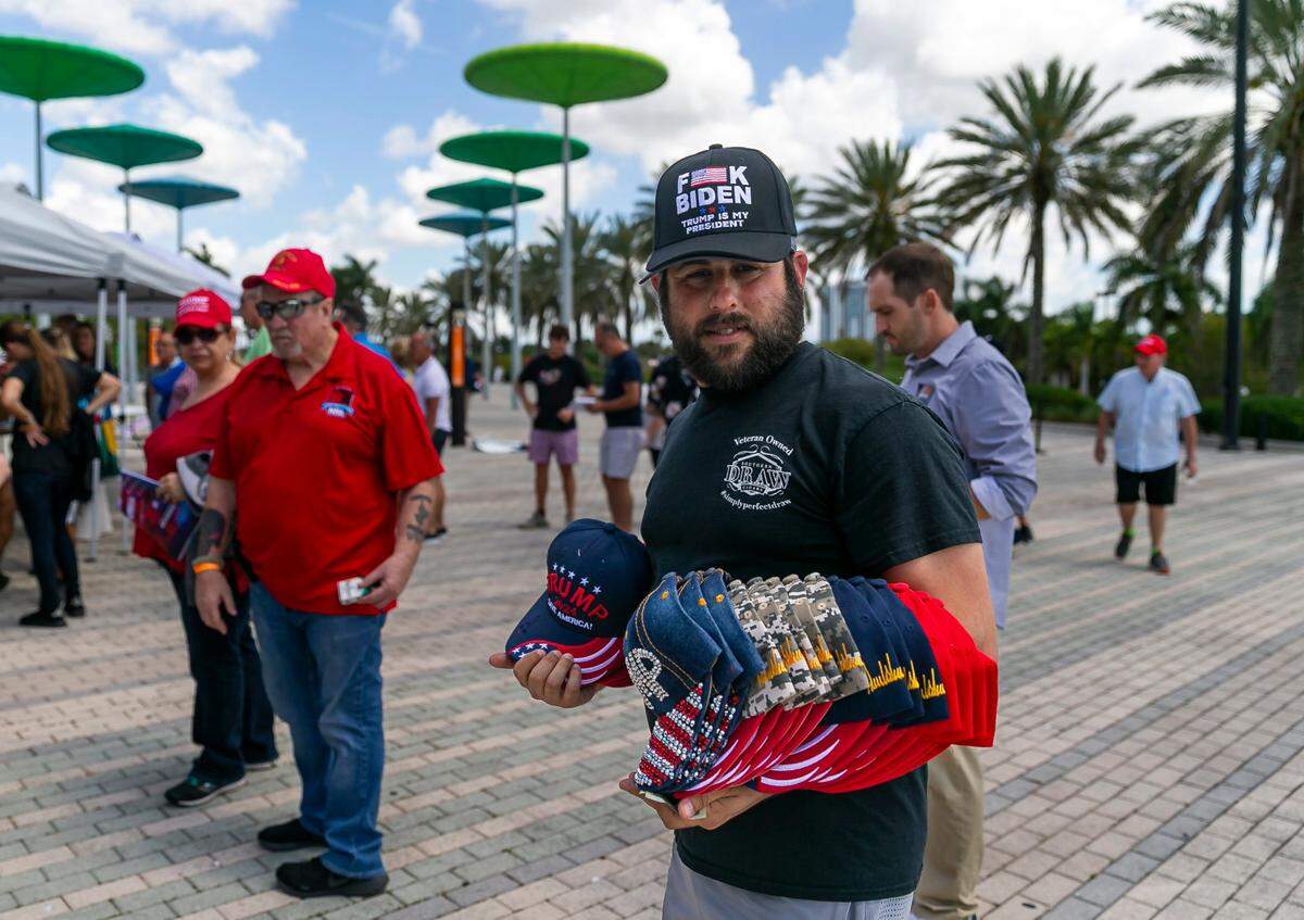 Steven Glazerman sells Donald Trump branded merchandise as people arrive to the American Freedom Tour at the FLA Live Arena in Sunrise, Florida on Saturday, March 19, 2022.