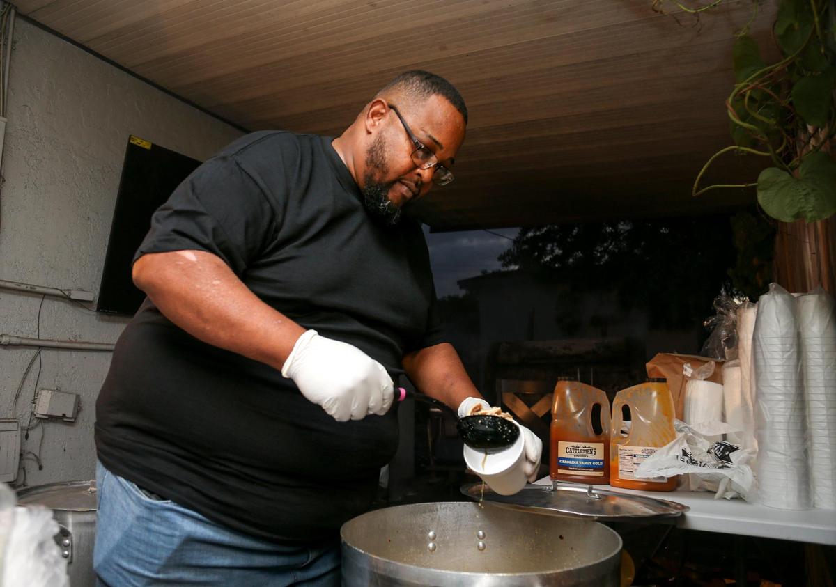 Larry D Reaves, 53, owner of World’s Famous Souseman BBQ, serves a cup of his famous pork stew in the backyard of his Opa-locka, Florida, home on Nov. 19, 2022.
