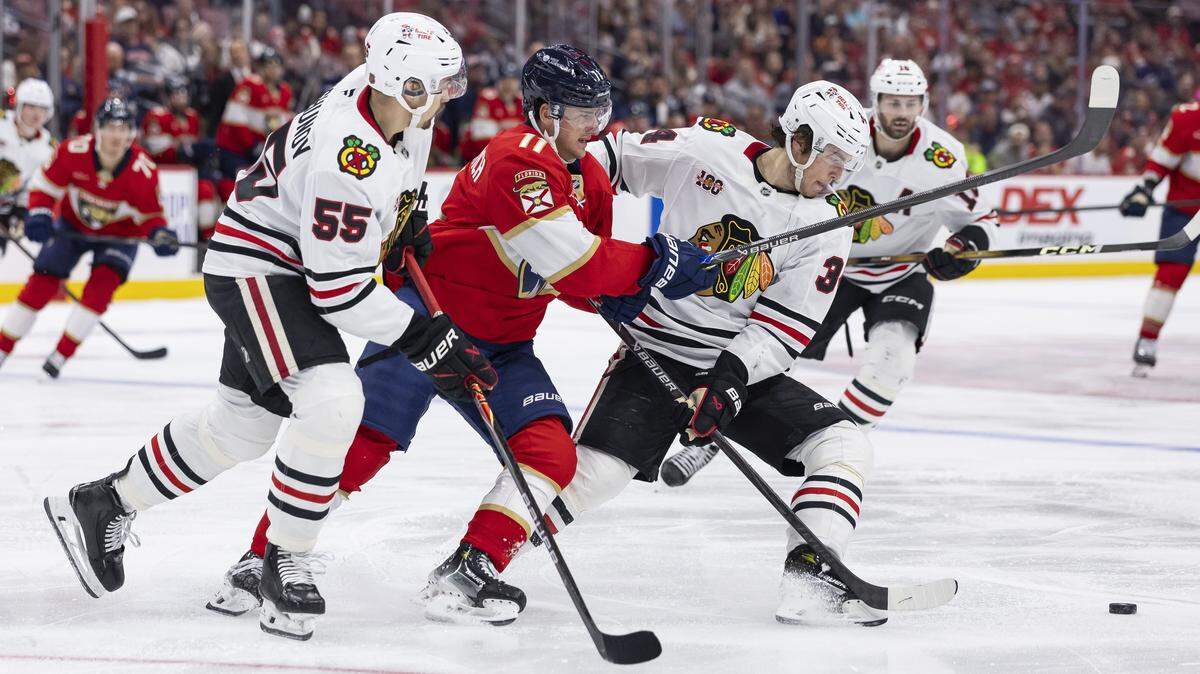 Florida Panthers right wing Mackie Samoskevich (11) competes for the puck gainst Chicago Blackhawks center Colton Dach (34) and defenseman Artyom Levshunov (55) in the third period of their NHL game at Amerant Bank Arena on Tuesday, Oct. 7, 2025, in Sunrise, Fla.