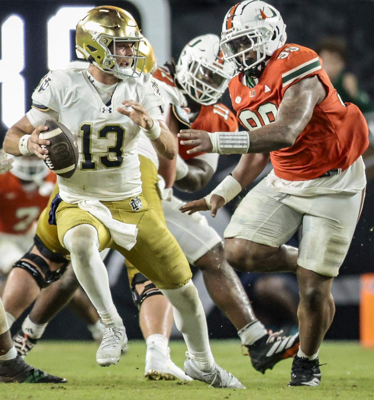 Miami Hurricanes defensive lineman Ahmad Moten Sr. (99) chases Notre Dame Fighting Irish quarterback CJ Carr (13) during the second half of an NCAA football game at Hard Rock Stadium in Miami Gardens, Florida, on Sunday, August 31, 2025.