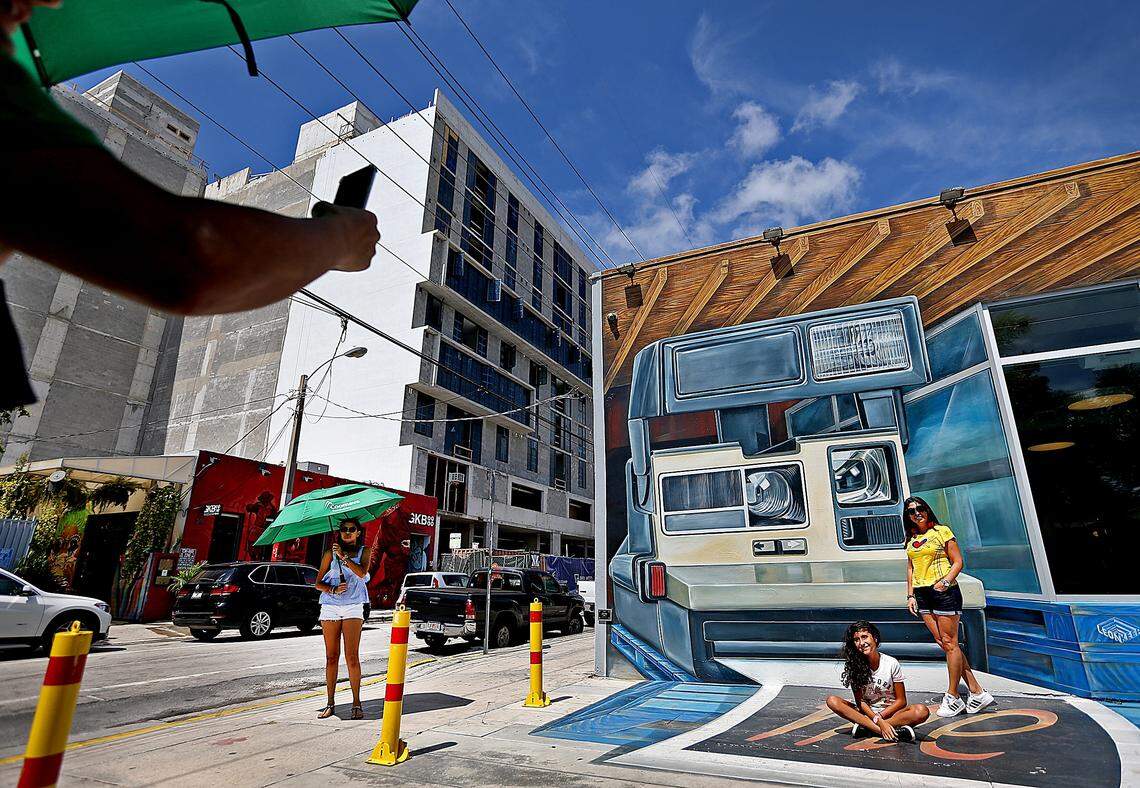 Omar Ramirez, visiting from Colombia,  takes pictures of his family by the colorful murals in Wynwood on Aug. 2, 2018.  The mural is  adjacent to ongoing office and condo construction.