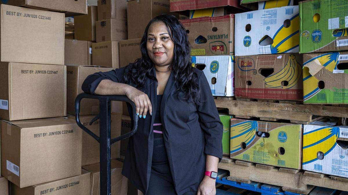 Miami, FL, October 23, 2025 -  Lavern Spicer, Executive Director of Curley’s House Hope Relief Food Bank, poses in front of boxes of food at a small storage space behind the food bank’s offices at 6025 NW Sixth Ct.