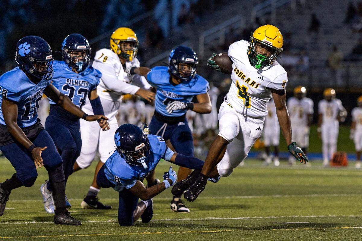 Killian High School running back Kayron Bryant (4) is tripped up by Palmetto High School safety Wynton Jones Jr. (8) during a high school football game at Tropical Park on Thursday, September 18, 2025, in West Park, Fla.