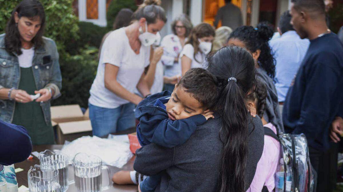 A woman, who is part of a group of immigrants flown to Martha’s Vineyard by Florida Gov. DeSantis, holds a child as they are fed outside St. Andrews Episcopal Church in Edgartown, Massachusetts.