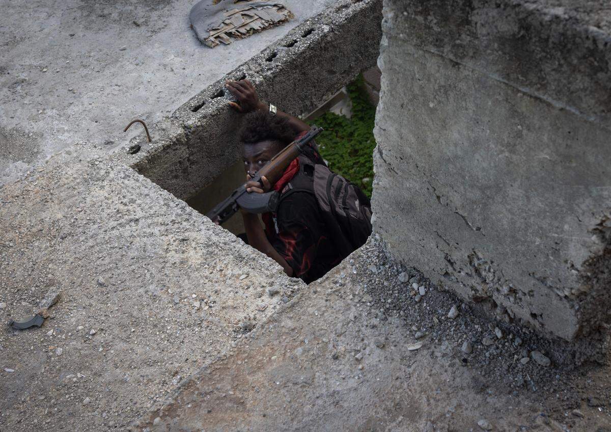 A gang member from the Viv Ansam coalition takes cover during a shoot-out with police in the Nazon neighborhood, Dec. 9, 2024.