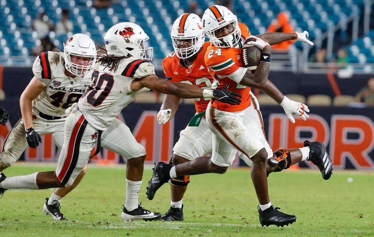 Miami Hurricanes running back Chris Johnson Jr. (24) on a carry as Ball State Cardinals defensive back Jalon Jones (30) defends in the second half of an NCAA football game at Hard Rock Stadium in Miami Gardens, Florida on Saturday, September 14, 2024.
