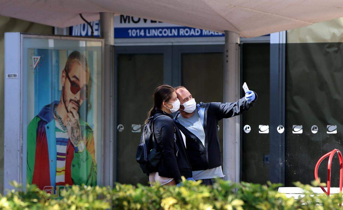 Tourists Valerie and Max, of Ukraine take a selfie as they waited for a bus at the Washington Ave and Lincoln Road corner early Tuesday morning, where few people are seen on the streets since all business are closed and all residents are urged to remain in their homes as the ÒSafer at HomeÓ orders in Miami-Dade made for an unusually quiet weekend despite plenty of sunshine in a region thatÕs typically buzzing with activity. There are now 4,950 confirmed cases of COVID-19 in Florida, state health officials announced Sunday night, an increase of 912 cases from the night before and the largest single-day jump to date. Sixty people in Florida have died of the disease. on Tuesday, March 31, 2020.