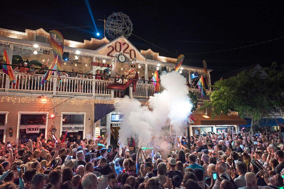 New Year’s Eve revelers celebrate outside the Bourbon St. Pub on Tuesday, Dec. 31, 2019, as “Sushi,” portrayed by female impersonator Gary Marion, is suspended above Duval Street outside the Bourbon St. Pub.