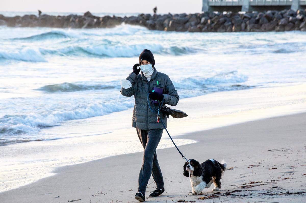 A woman walks with her dog near South Pointe Park Pier as the sun rises on Miami Beach, Florida in this Dec. 26, 2020 file photo.