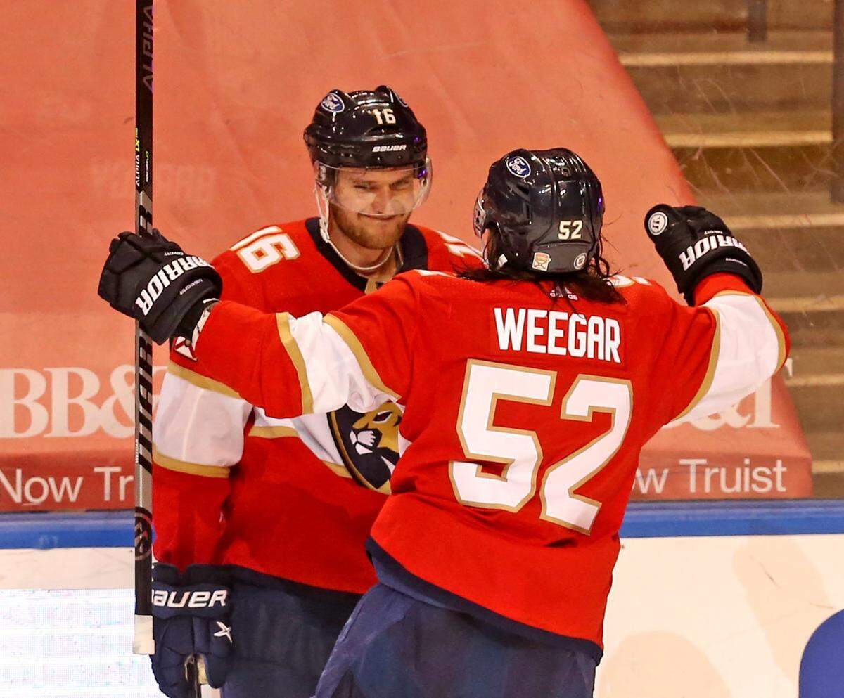Florida Panthers MacKenzie Weegar (52) grabs Aleksander Barkov (16) after Barkov scored the winning goal in overtime as they defeat the Carolina Hurricanes at the BB&T Center in Sunrise, Florida, Saturday, April 24, 2021.