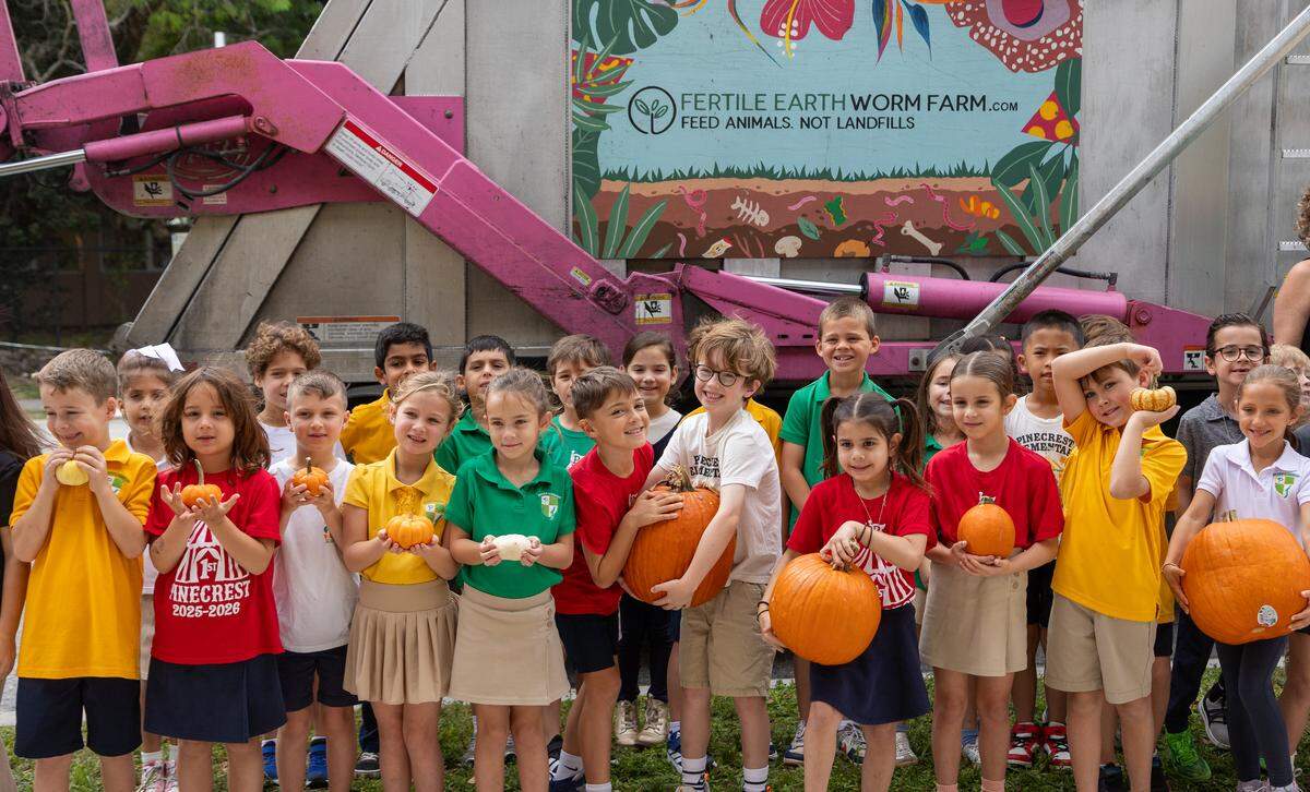 Students from Mrs. Armenteros and Miss. Salazar’s first grade class pose with pumpkins in front of the Fertile Earth Worm Farm composting truck.