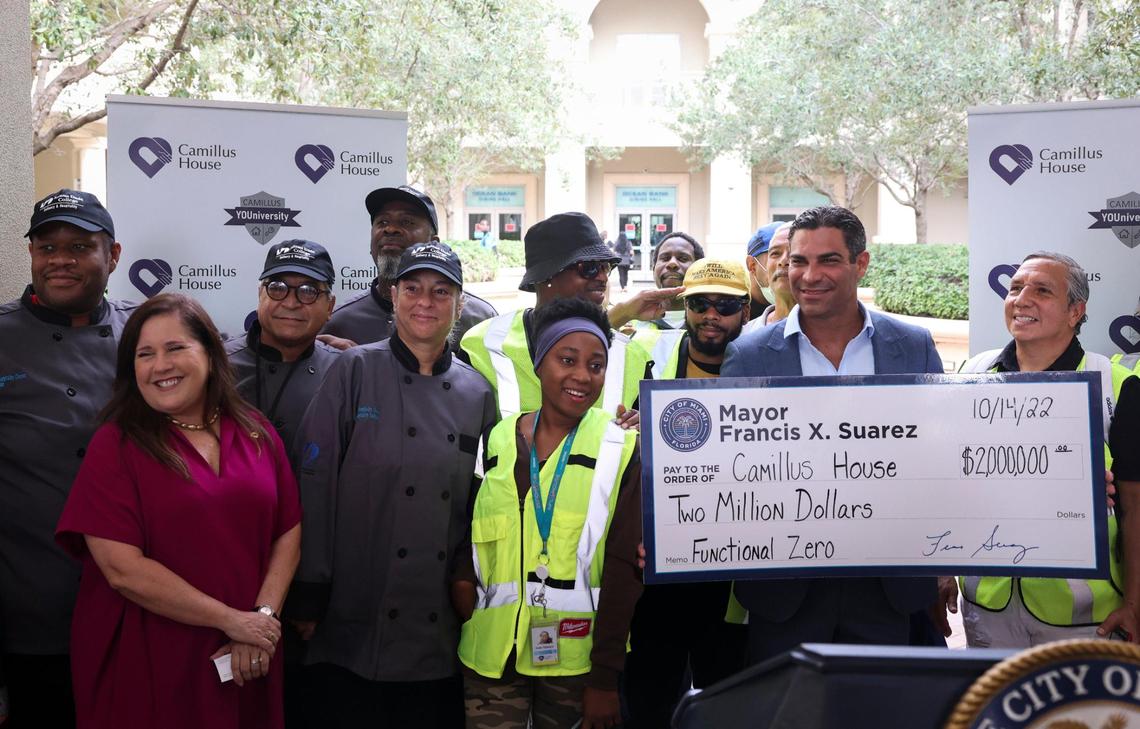 Miami Mayor Francis Suarez, right, holds a check for Hilda Fernandez, left, CEO of Camillus House, after a press conference announcing a $2 million city donation to Camillus House as part of the “Functional Zero” homeless plan on Friday, Oct. 14, 2022, in Miami.