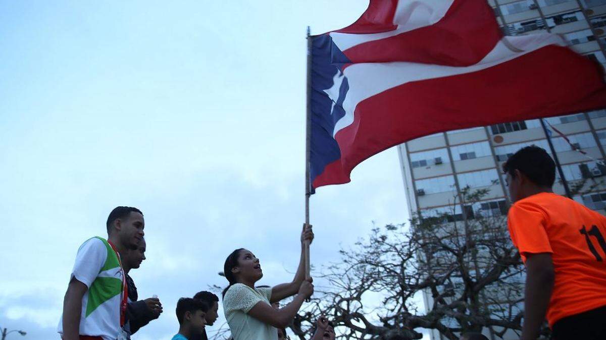 People wave a Puerto Rican flag outside the Torres de Francia complex in San Juan, Puerto Rico, after Hurricane Maria blew through in 2017.