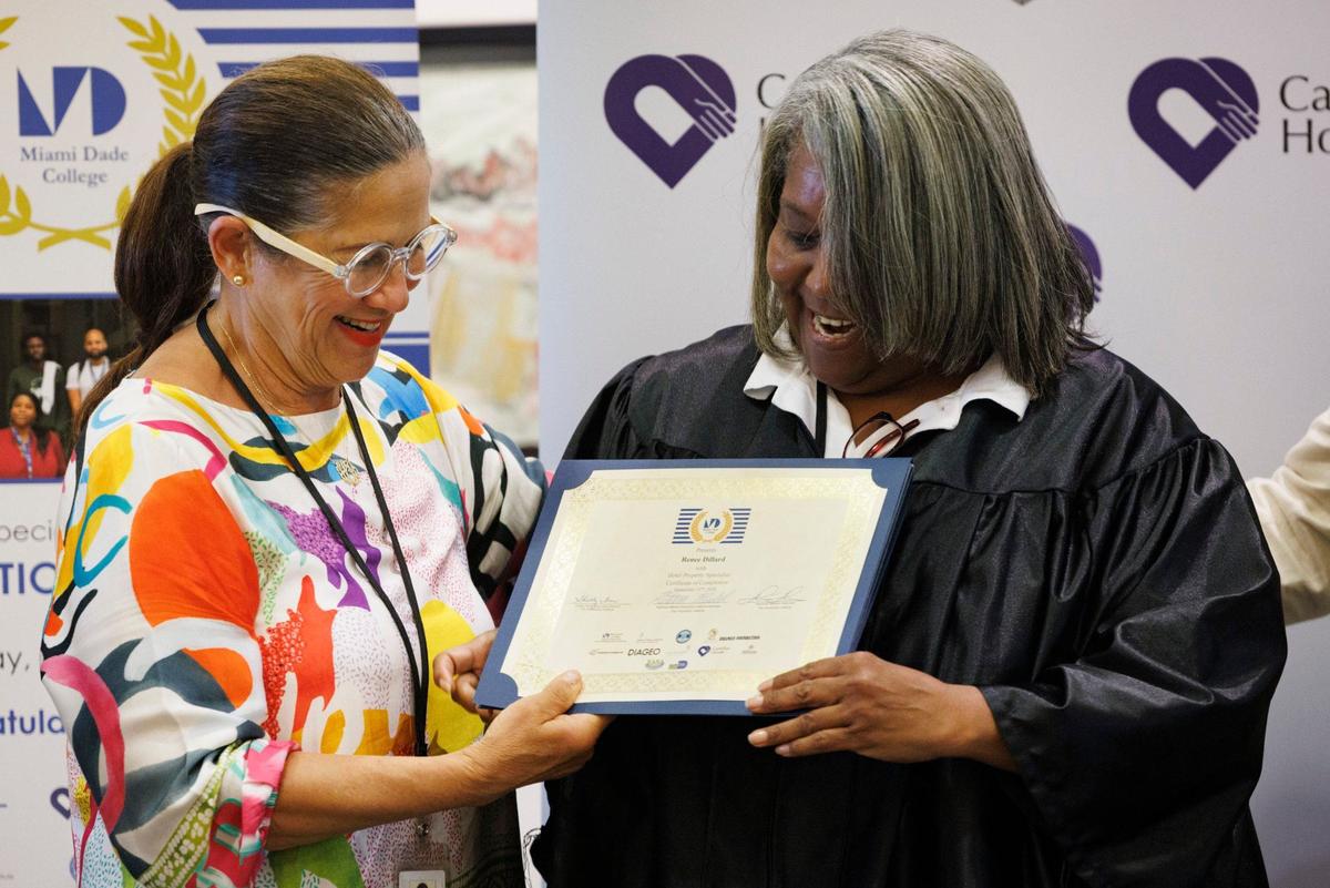 Herminia Herrera, a Hospitality Institute instructor, hands a certificate of completion to Renee Dillard during her graduation ceremony for the Hotel Property Specialist program on Wednesday, Sept. 11, 2024, at Camillus House in Miami.
