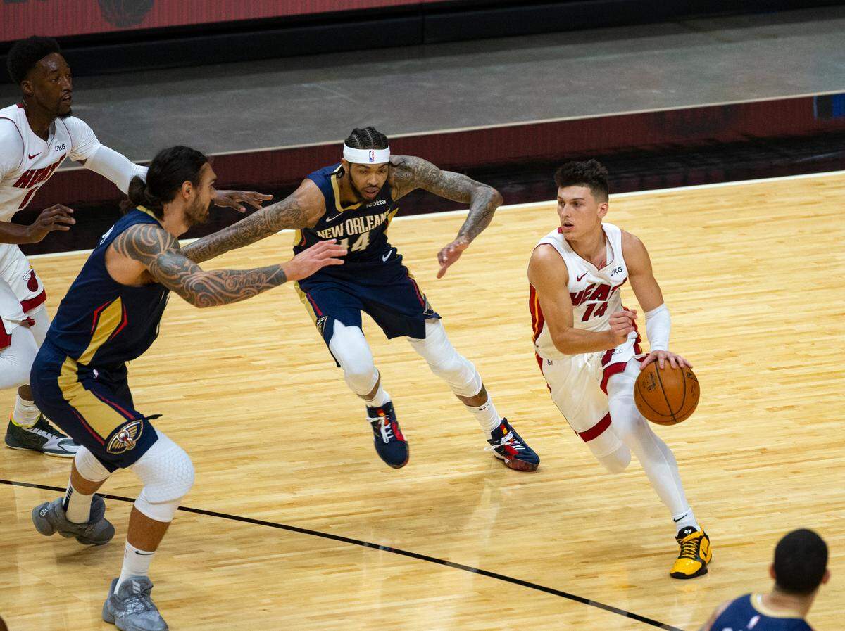Miami Heat guard Tyler Herro (14) drives against New Orleans Pelicans center Steven Adams (12) and Brandon Ingram (14) in the first quarter of an NBA basketball preseason game at AmericanAirlines Arena on Monday, Dec. 14, 2020.