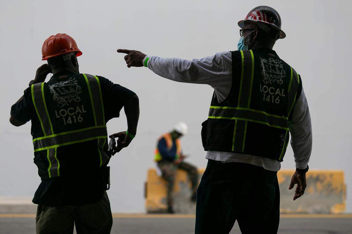 Longshoremen Thomas Rhome, left, and Keith Reaves, right, wait to unload a truck at the Norwegian Cruise Line Terminal in PortMiami on Tuesday, February 16, 2021.