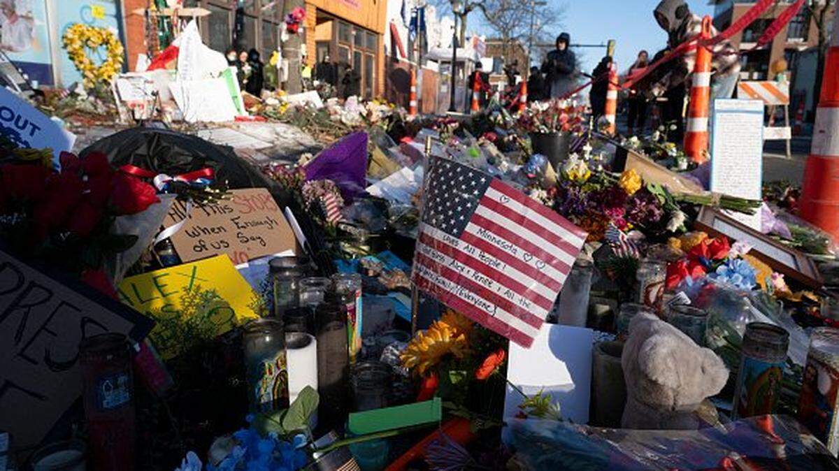 People gather at a makeshift memorial in the area where Alex Pretti was shot dead by federal immigration agents in Minneapolis, Minnesota, on January 28, 2026. US President Donald Trump said on January 27 that he would "de-escalate a little bit" in Minneapolis after the fatal shootings of two civilians fueled a storm of criticism over his signature immigration crackdown. Trump's "border czar" Tom Homan met with officials in the city as the Republican attempted damage control after the killing by immigration agents of 37-year-old nurse Alex Pretti on Saturday. (Photo by ROBERTO SCHMIDT / AFP via Getty Images)