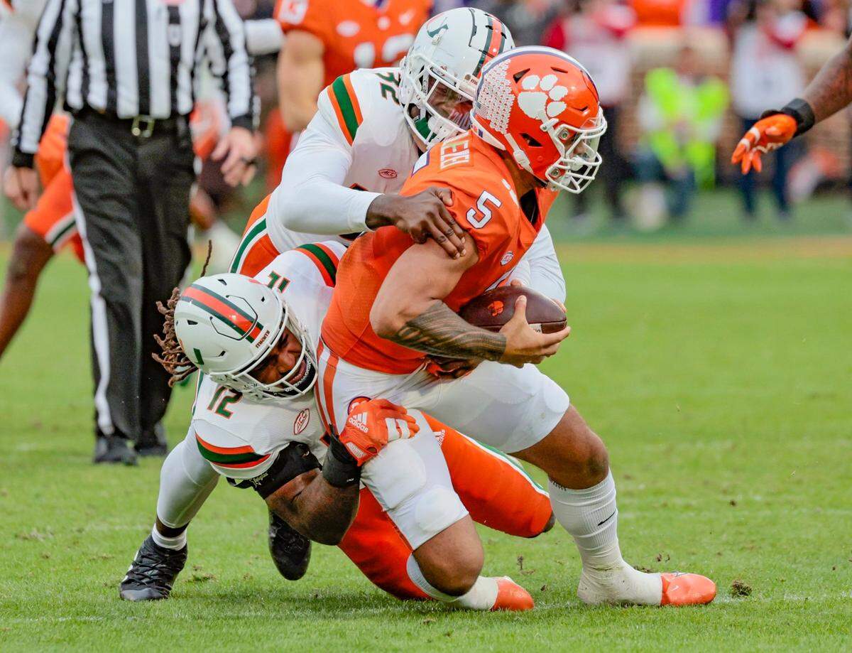 Miami Hurricanes defensive lineman Nyjalik Kelly (32) and defensive lineman Jahfari Harvey (12) Clemson Tigers quarterback DJ Uiagalelei (5) in the first quarter at Frank Howard Field at Clemson Memorial Stadium in Clemson, South Carolina on Saturday, November 19, 2022.