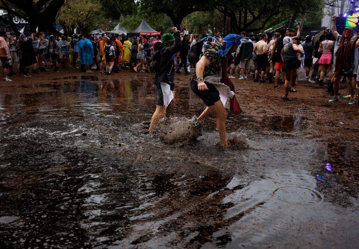Attendees dance in a huge water puddle after a rainstorm during the third day of Ultra Music Festival on Sunday, March 30, 2025, at Bayfront Park in downtown Miami, Fla. The festival closed its doors for about a half hour urging fans to take cover from the lightning and rain, but then opened back up after it passed.  