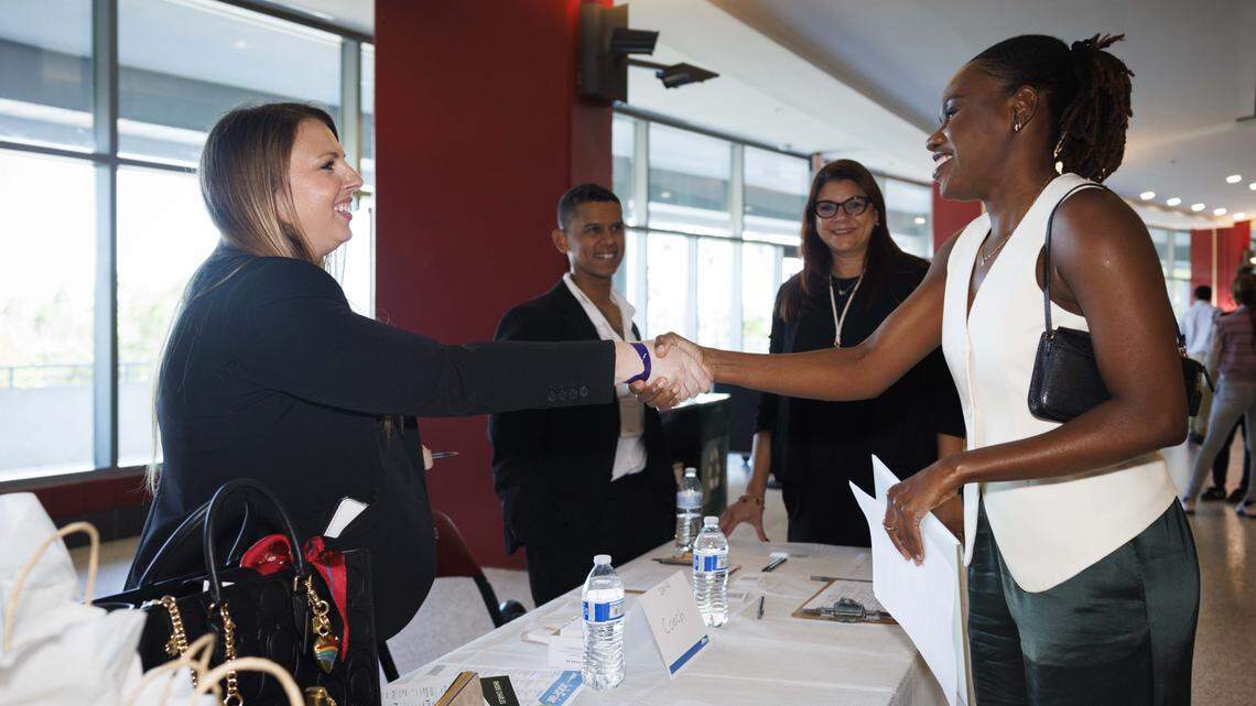 Megan Lucchese, Coach store manager at Sawgrass Mills, left, shakes hands with a potential candidate during the Job News South Florida Job Fair on Thursday, Oct. 30, 2025, at Amerant Bank Arena in Sunrise, Fla.