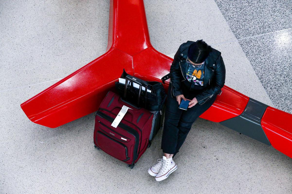 A traveler uses her phone as she waits at Miami International Airport in Miami, Florida, on Monday, November 22, 2021.