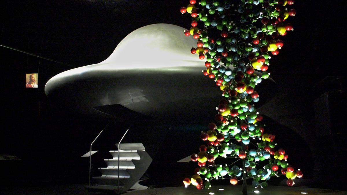 A 10-foot rotating model of a human gene and what Raelians claim to be an exact replica of a flying saucer seen by their leader Rael, stand beside a hanging portrait of Jesus inside a room at UFO Land, Raelian headquarters, in Valcourt, Quebec. Clonaid, a company started by the Raelians recently claimed to have developed the first cloned baby called Eve.