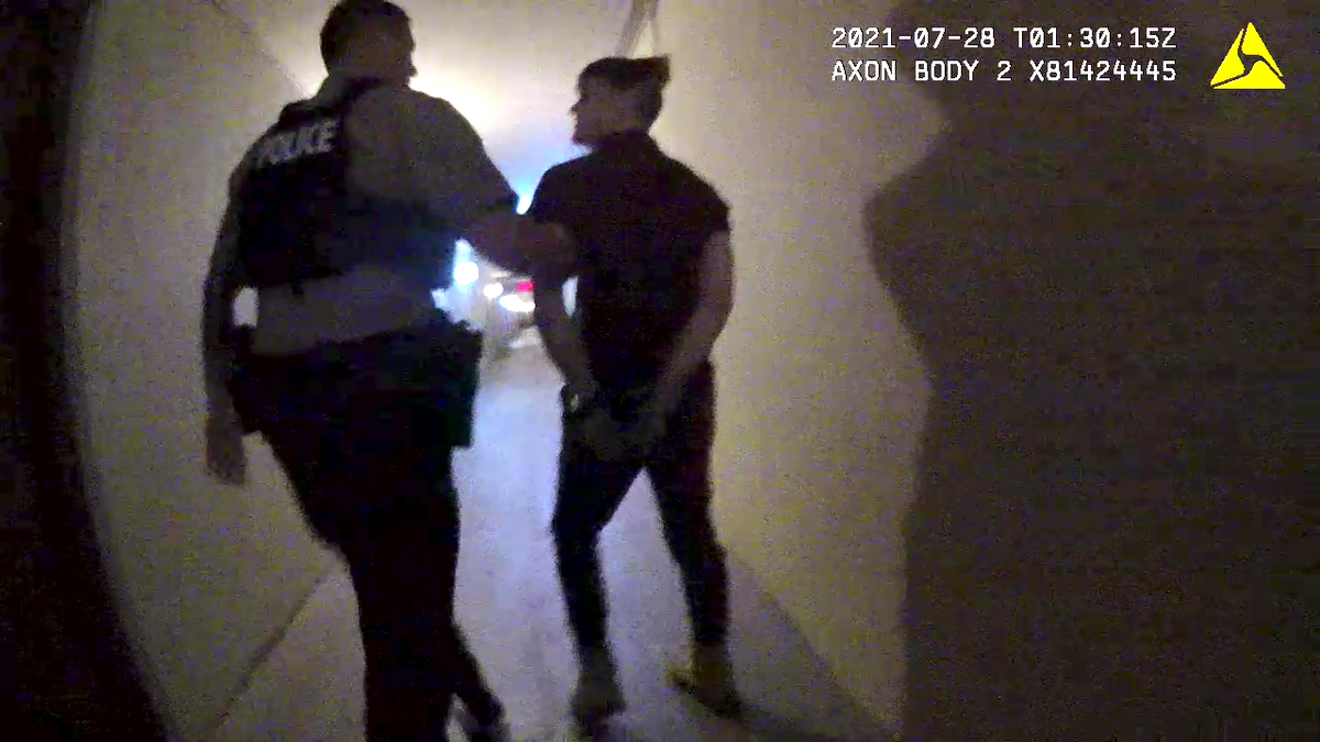 A Miami-Dade police officer leads Richard Hollis to the police car after an arrest on July 28, 2021.