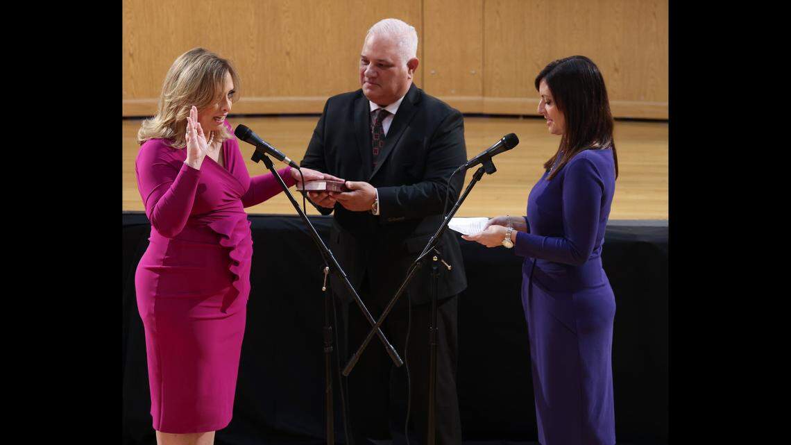 Standing with her husband Eudald “Eddy” Lopez, center, newly elected Miami-Dade School Board member, Monica Colucci, left, places her hand on the Bible as she is sworn-in at the Miami-Dade School Board headquarters on Tuesday, Nov 15, 2022, Lt. Governor of Florida Jeanette Nuñez unofficially swore in Colucci, who will be officially sworn in on Nov. 22. CARL JUSTE cjuste@miamiherald.com