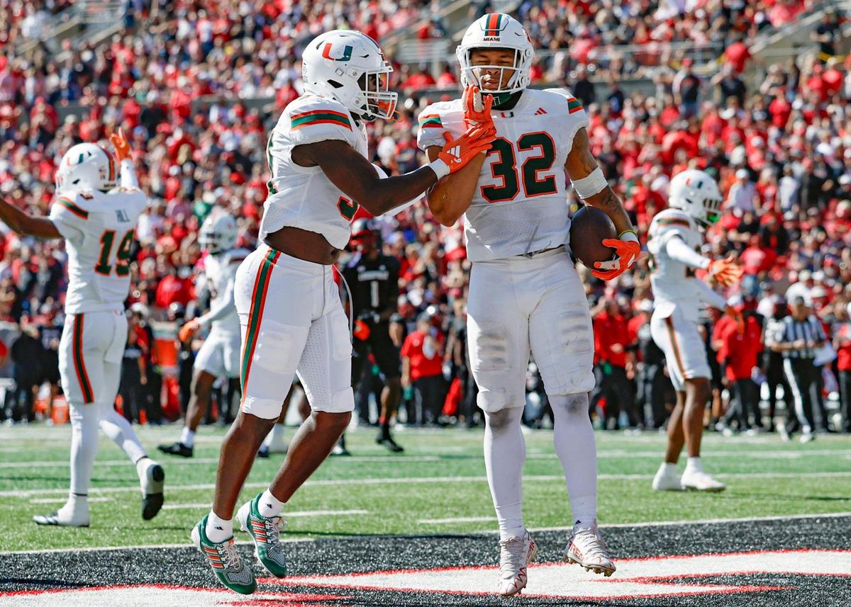 Miami Hurricanes linebacker Raul Aguirre Jr. (32) and linebacker Wesley Bissainthe (31) celebrate Aguirre’s fumble recovery for a touchdown in the first half against the Louisville Cardinals during an NCAA football game at L&N Federal Credit Union Stadium in Louisville, Kentucky on Saturday, October 19, 2024.