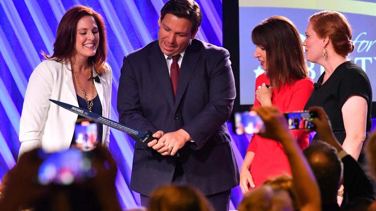 Florida Governor Ron Desantis, center, is presented “The Sword of Liberty” by Moms for Liberty co-founders Tiffany Justice, left, Tina Descovich, second from the right, and executive director of program outreach Marie Rogerson, far right, during the first Moms for Liberty National Summit on Thursday, July 15, 2022, in Tampa, Florida. The convention continues through Sunday, July 17th with conservative speakers and strategy sessions for members.