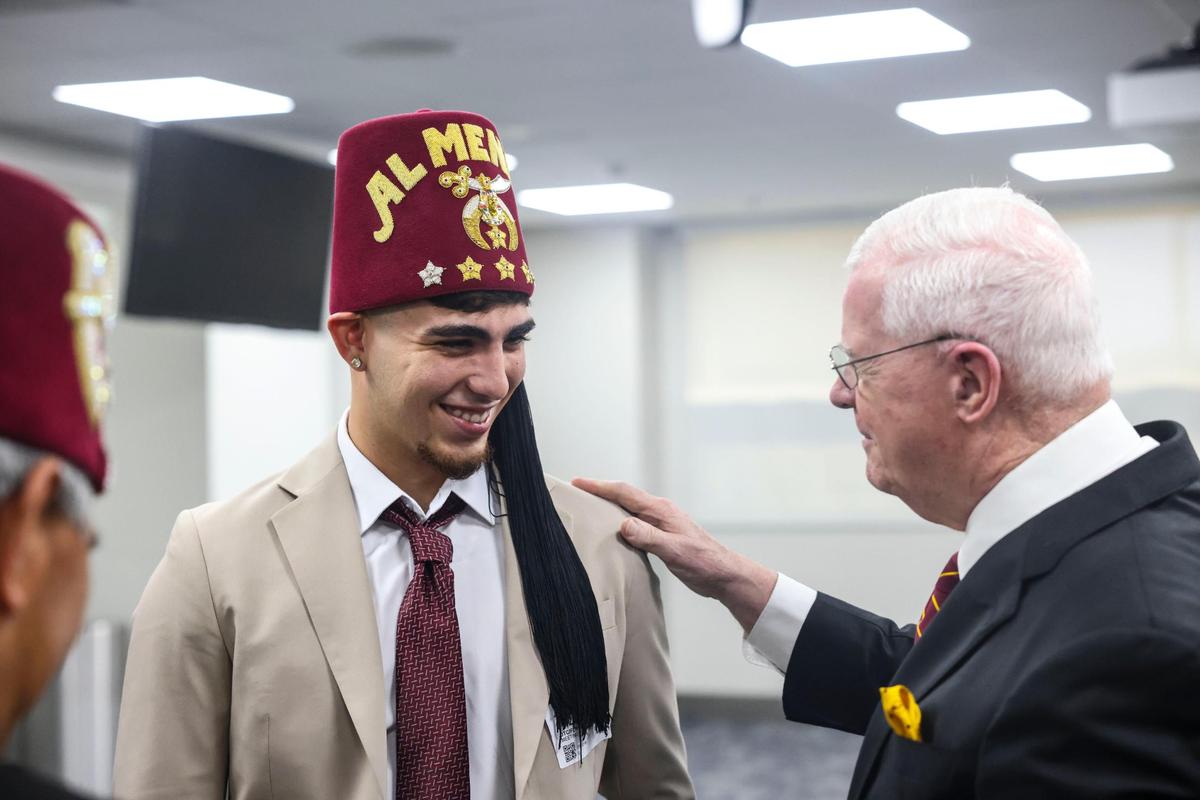 Brayan Solano, left, pediatric patient at the Tampa Shriners Children’s Florida, gets a Shriner hat put on him during a press conference announcing Jackson, UHealth and Shriner’s Children’s Florida partnership and the opening of a new kids’ orthopedic center on Friday, July 22, 2022, at Jackson’s Diagnostic treatment center.