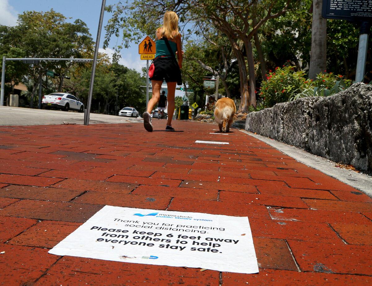 The City of Miami urges residents to keep social distance during the coronavirus pandemic as they come to the public library on Tuesday, April 14, 2020, to pick up or drop off unemployment applications in Coconut Grove.
