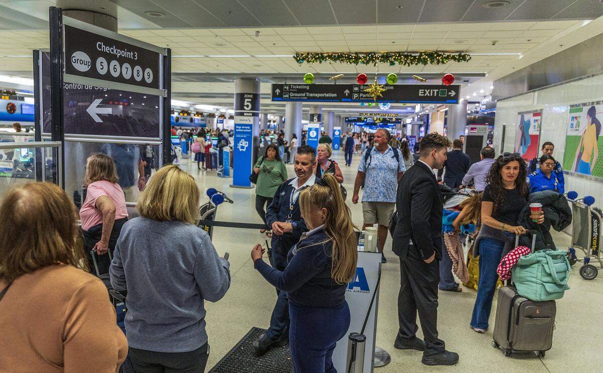 Employees guide passengers as they entered checkpoint three in Concourse D, at Miami International Airport ahead of the Holidays in Miami, on Friday, November 21, 2025.