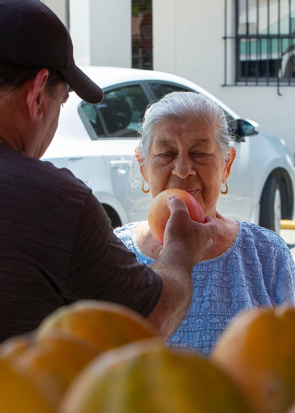 Arturo Tamayo holds a fresh mango out for a patron at his bodega truck while stopped outside a senior center in Miami, FL, on Wednesday, June 20, 2018.