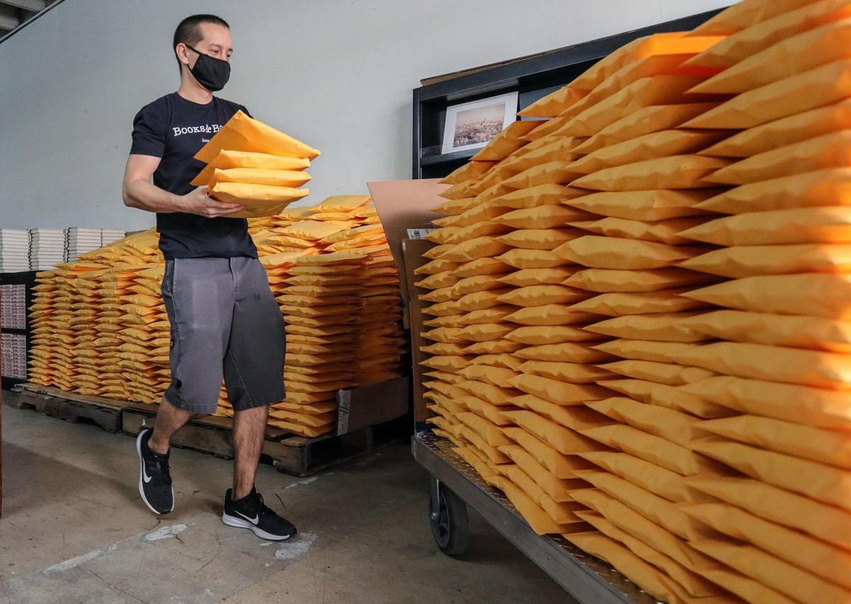 Books & Books employee Sean Bauza stacks holiday book orders that are shipping out of the company warehouse on Thursday, December 17, 2020.