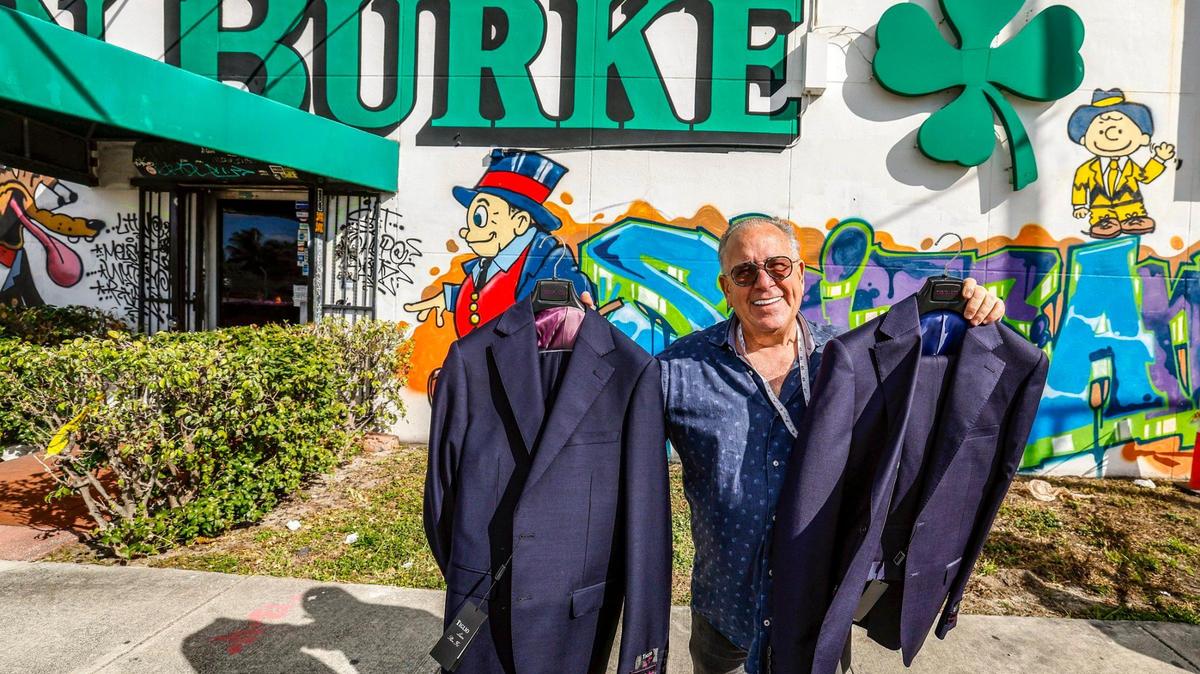 Austin Burke co-owner Kenny Sager steps outside the store with a couple of suits near Wynwood in Miami, Florida on Friday, Jan. 10, 2025. The men’s clothing retail store has been in Miami since 1955, founded by the namesake. He died in 1987. His son Barry Burke and business partner Sager have run and owned the Miami store after graduating from Miami Beach High. Burke and Sager have sold the distinctive white cinderblock building with the green shamrock logo they bought for $300,000 for $8m. Both 68, they have decided to close the store to retire.