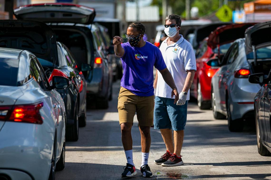 Jared Romance, 30, directs cars during a drive-thru distribution event at Joseph C. Carter Park in Fort Lauderdale, Florida on Saturday, Aug. 8, 2020. Volunteers distributed food, sanitation items, backpacks and back-to-school necessities during the 8th Annual Sunshine Health Orange Bowl Family, Fun & Fit Day drive-thru only event.