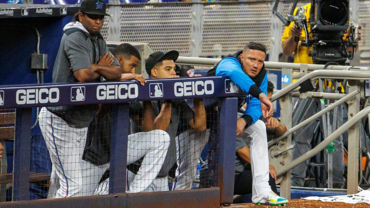 Miami Marlins players Edward Cabrera (27) Sandy Alcantara (22) Jesus Luzardo (44) and Miguel Rojas (11) look from the dugout during the ninth inning of a baseball game against the San Diego Padres at LoanDepot Park on Wednesday, August 17, 2022 in Miami, Florida.