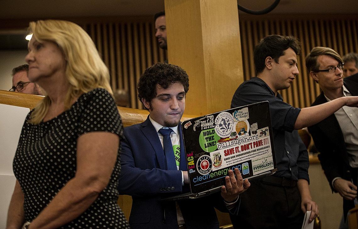 Zac Cosner of Pinecrest looks at his computer that is adorned with a Hold the Line sticker as he waits in line to address the Miami-Dade commission at a public hearing and commission meeting  on Thursday, Sept. 27, 2018, to decide whether to extend State Road 836 into West Kendall.