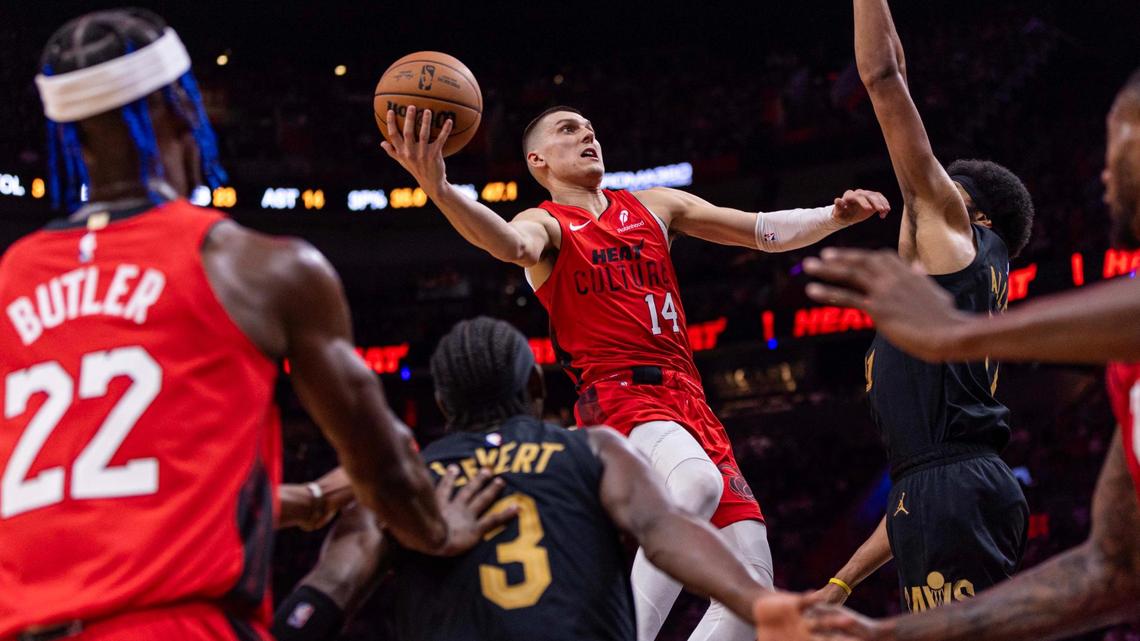 Miami Heat guard Tyler Herro (14) hangs in the air before scoring off a lay up over Cleveland Cavaliers guard Caris LeVert (3) and center Jarrett Allen (31) during the second half of an NBA game at the Kaseya Center on Sunday, Dec. 8, 2024, in Miami, Fla.