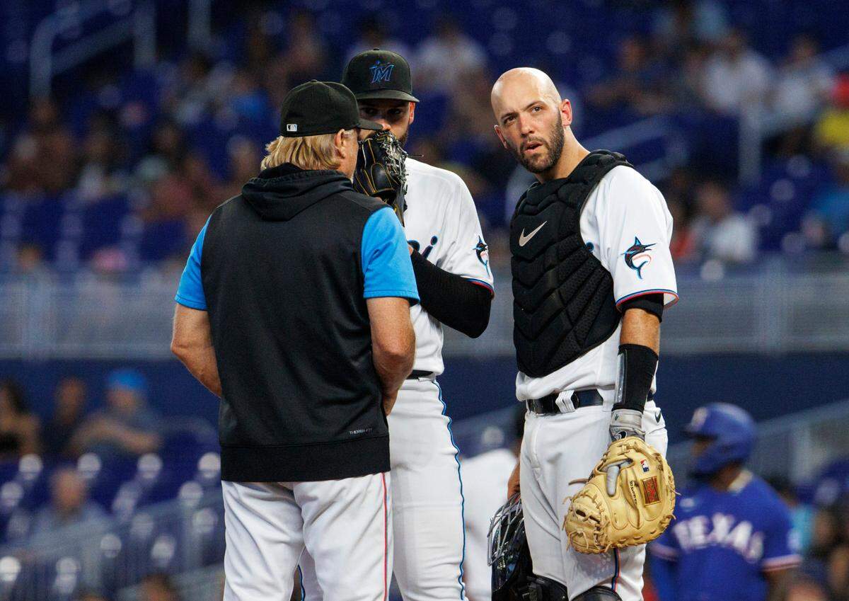 Miami Marlins starting pitcher Pablo Lopez (49) talk with Marlins pitching coach Mel Stottlemyre Jr. and catcher Jacob Stallings (58) during the third inning of a baseball game against the Texas Rangers at LoanDepot Park on Thursday, July 21, 2022 in Miami, Florida.