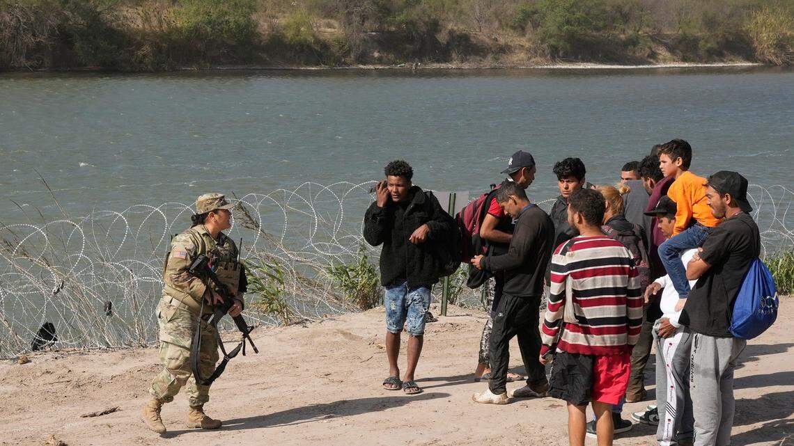 An Army National Guard soldier talks to migrants from Venezuela near the Rio Grande before they surrendered to U.S. Border Patrol on Jan. 8.