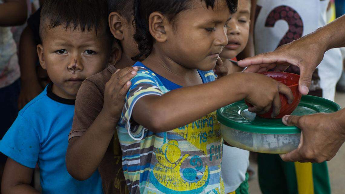 Food is given out to indigenous and Venezuelan refugee children in the Colombian river town of Puerto Inírida, which acts as a supply depot and transit point for Venezuela’s nearby illegal gold mining industry.