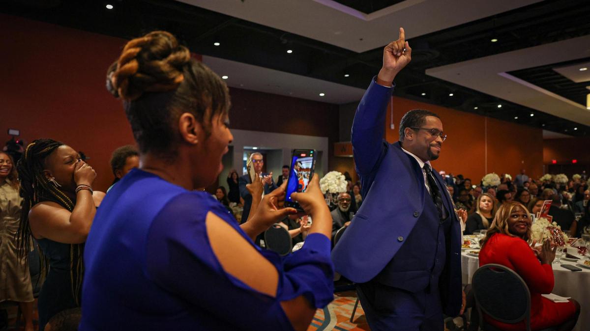 Don Clerveaux, a science and social studies teacher at Phyllis Ruth Miller Elementary, right, reacts after he was named 2024​ Francisco R. Walker Teacher of the Year for Miami-Dade County Public Schools. His wife, Carmen records the moment during the ceremony at the DoubleTree by Hilton Hotel Miami Airport and Convention Center, Tuesday night, Jan. 31, 2023.