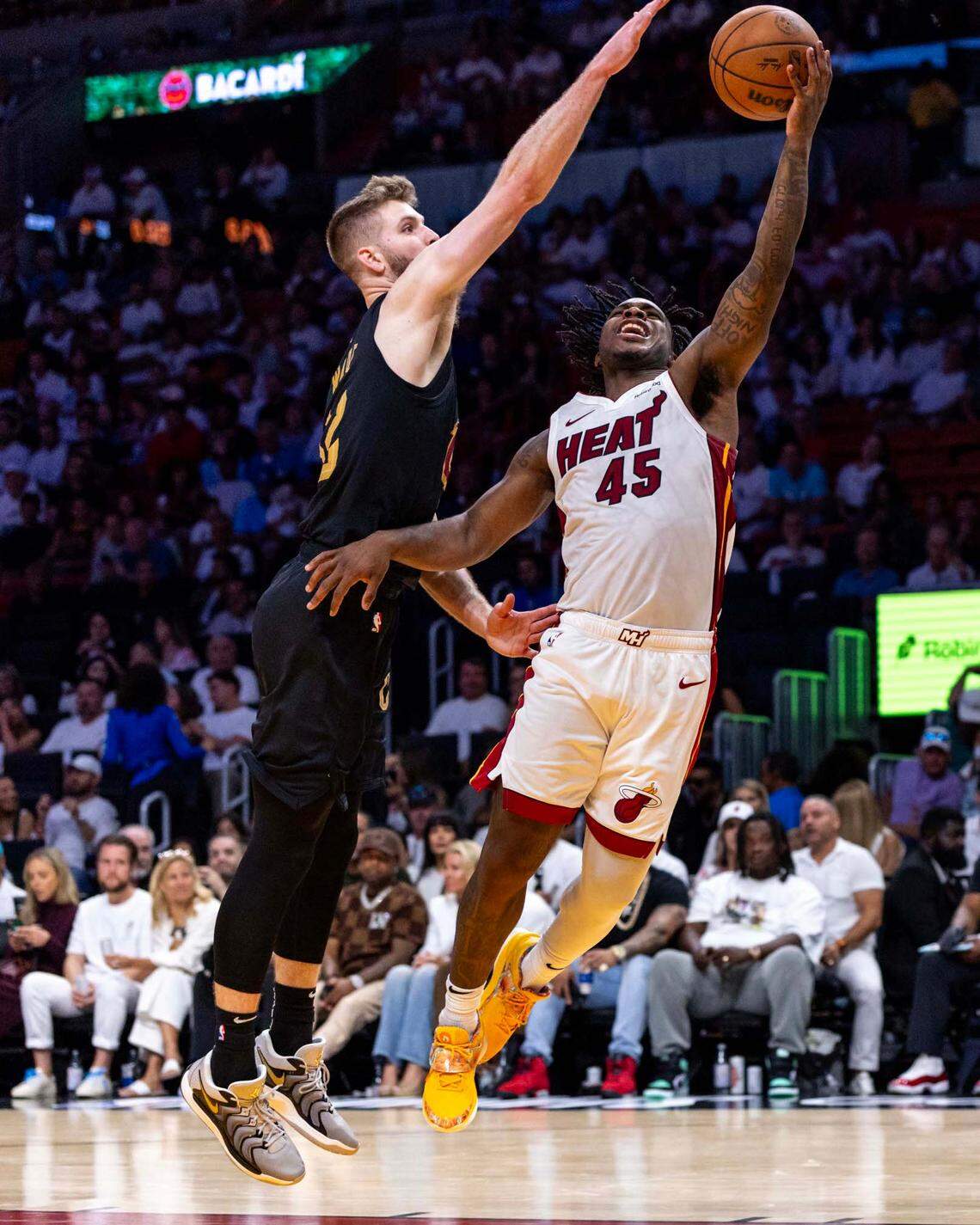 Miami Heat guard Davion Mitchell (45) lays up the ball around Cleveland Cavaliers forward Dean Wade (32) during the second half of Game 3 of the NBA Playoffs at Kaseya Center on Saturday, April 26, 2025, in Miami, Fla.