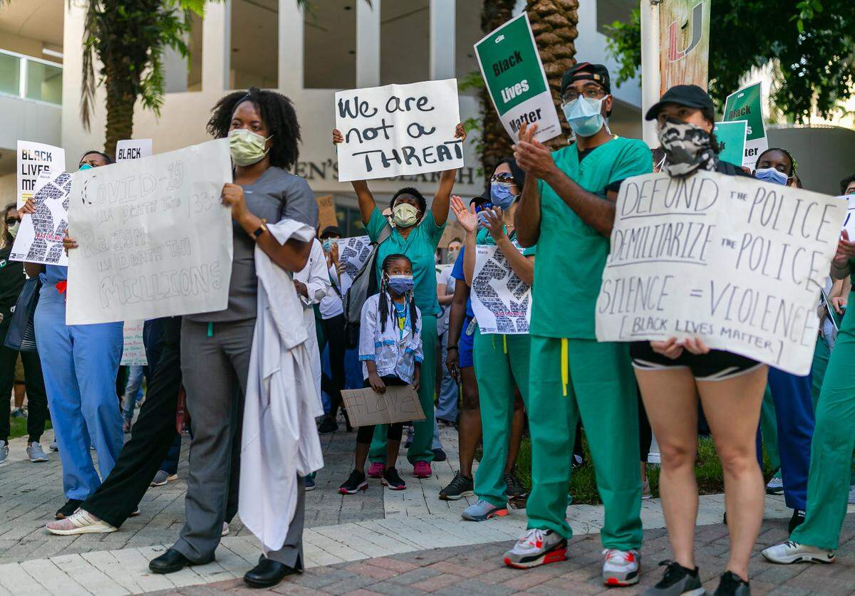 Zuri Copeland, 7, center, and her mother, Valencia Copeland, behind her, attend a White Coats for Black Lives rally near Jackson Memorial Hospital in Miami, Florida, on Tuesday, June 9, 2020.