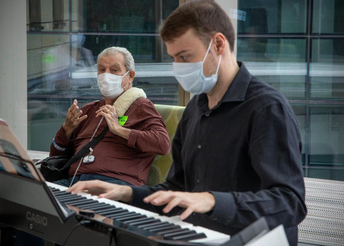 Yianni Iliadis plays the piano as patient Robert Tascione listens while waiting in the lobby at the Miami Cancer Institute at Baptist Health South Florida in Miami on Wednesday, May 12, 2021. The artists in residence provide cancer support therapy services with art and music.