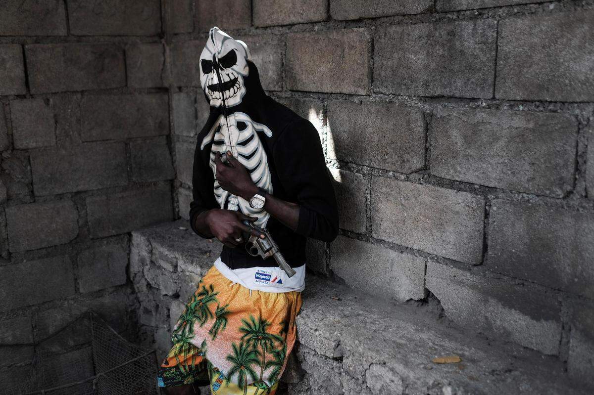 A gang member poses with his revolver before a rally to demand justice for slain Haitian President Jovenel Moïse in the La Saline neighborhood of Port-au-Prince, Haiti, Monday, July 26, 2021. As conditions have deteriorated, gangs have been driving people from their homes in the impoverished neighborhoods of Port-au-Prince.