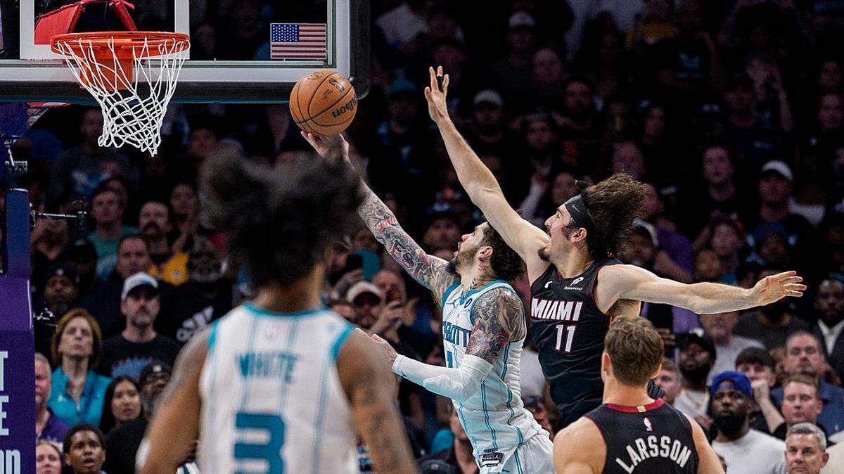 LaMelo Ball #1 of the Charlotte Hornets makes a layup while guarded by Jaime Jaquez Jr. #11 of the Miami Heat in overtime during their game at Spectrum Center on April 14, 2026 in Charlotte, North Carolina.